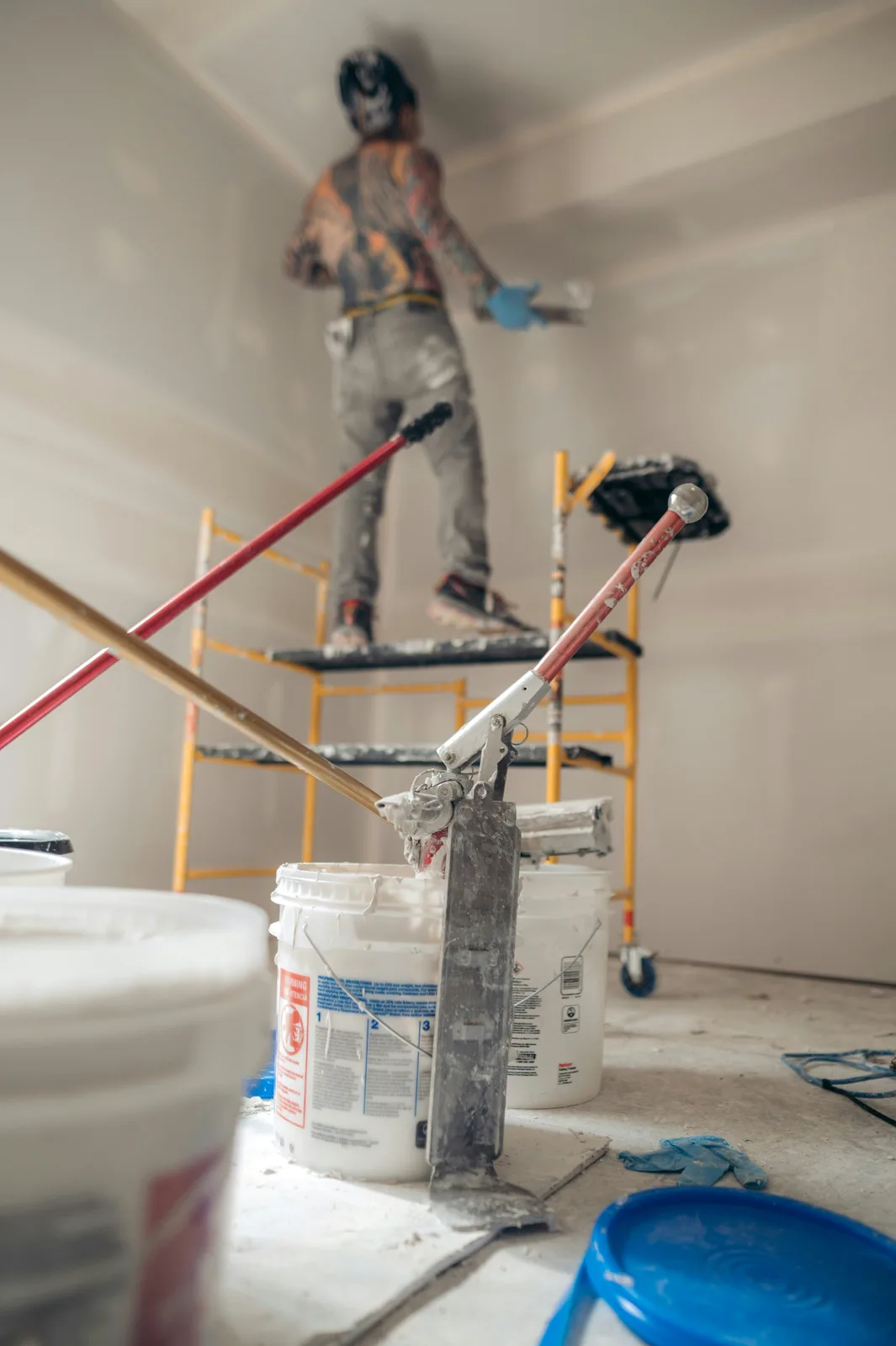 Drywaller taping walls from a rolling scaffold