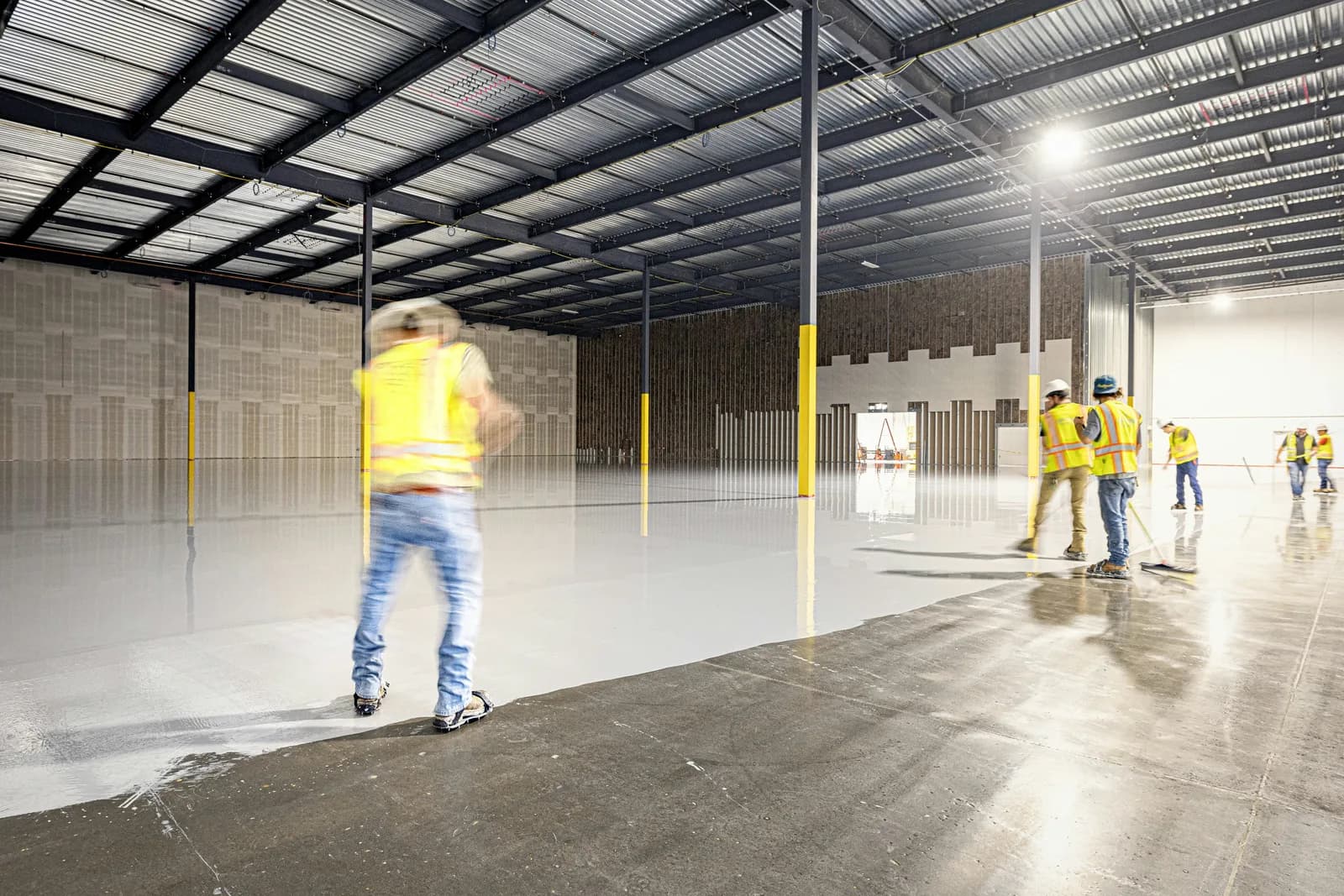 Crew applying epoxy floor coating in a warehouse
