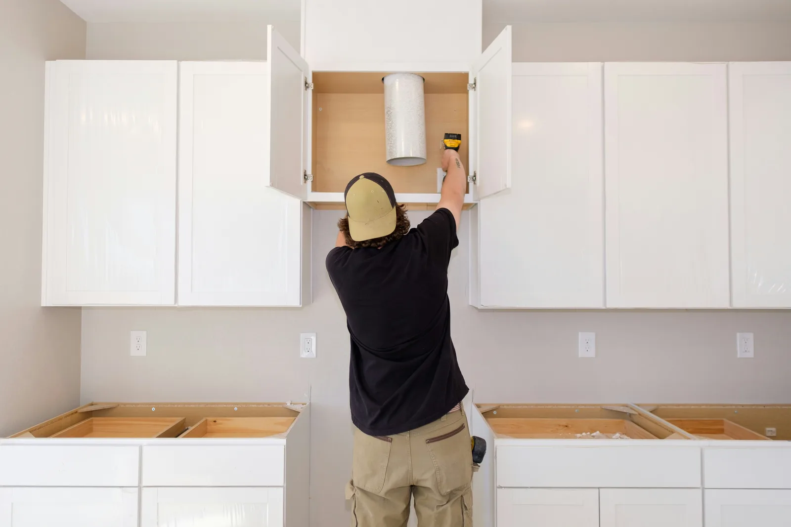 Installer mounting kitchen cabinets