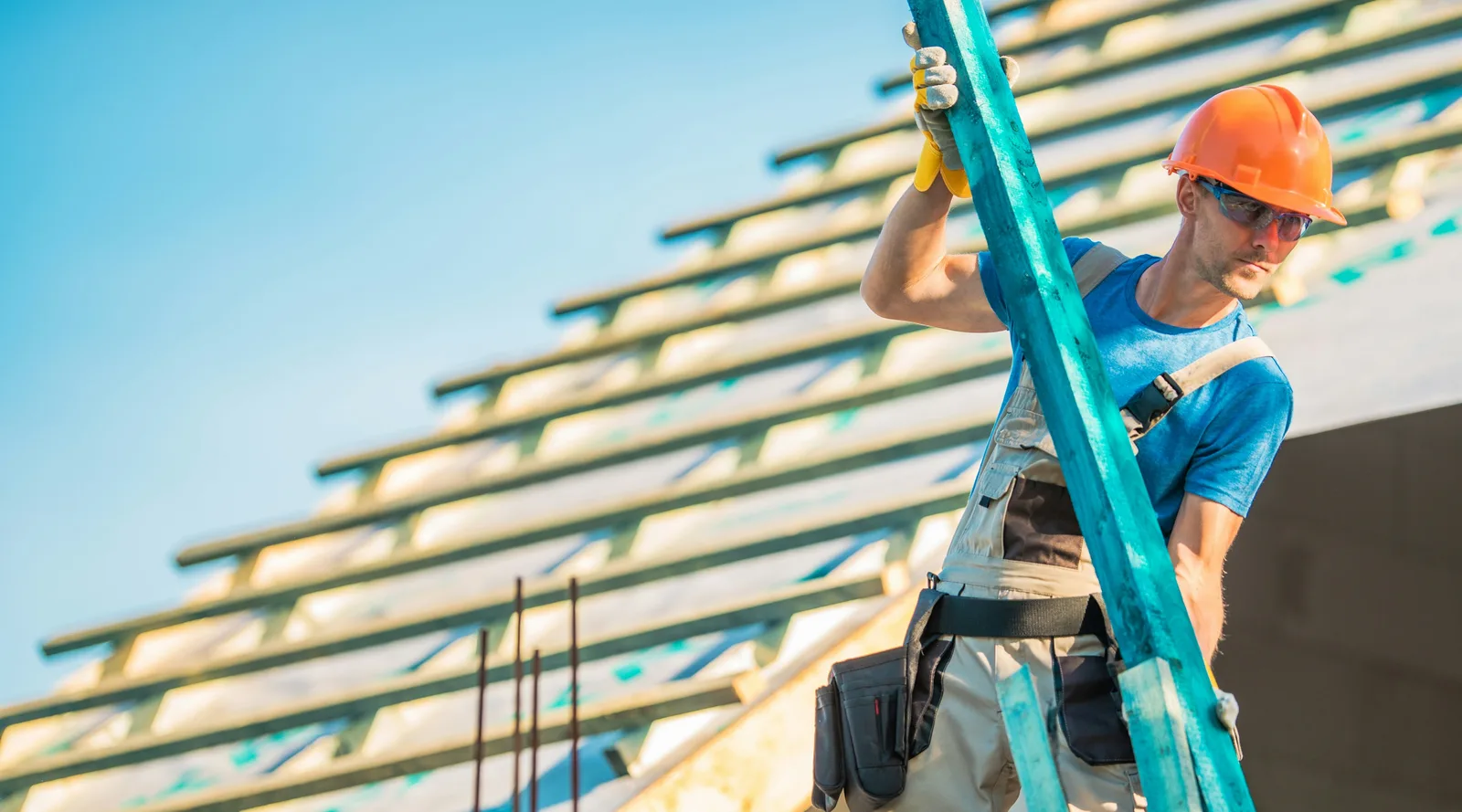 Roofer carrying a beam on a roof frame