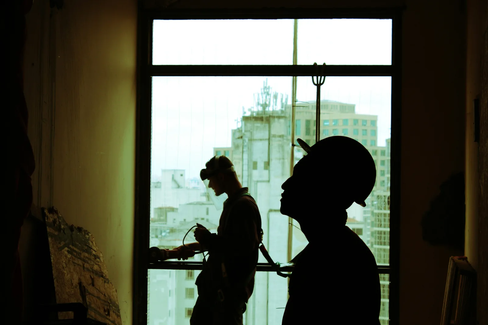 Construction workers silhouetted against a city skyline